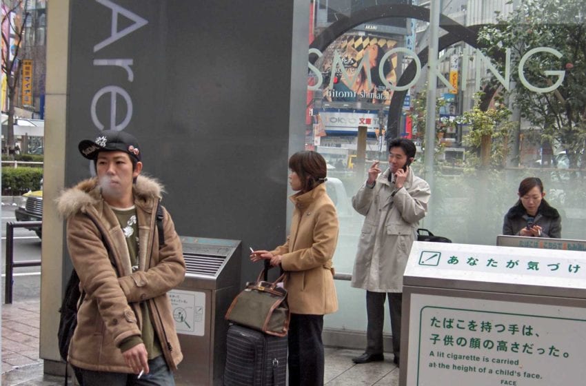 Japenese smokers congregating in an outdoor smoking area in Tokyo